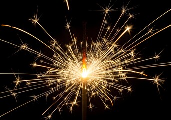 Golden sparkler bursts with radiant sparks against black background for festive, holiday, or celebration use

