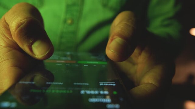 Close-up of a trader's finger scrolling through a financial graph on a digital device at night