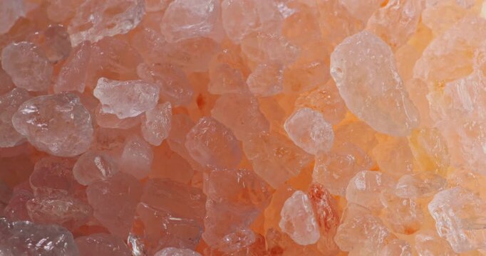 Pink Himalayan Salt Crystals Seamless Loop. Close-up macro view of coarse rose-colored Himalayan salt grains gently sparkling under soft lighting.	
