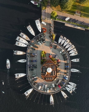 Aerial view of boats docked in a circular harbor, the water reflecting the golden light of the late afternoon, Lemmer, Friesland, Netherlands.