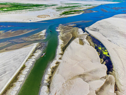 Aerial view of winding rivers carving through vast expanses of sandbars, creating a mesmerizing tapestry of textures and tones, Bogura, Rajshahi Division, Bangladesh.