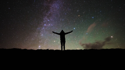 Silhouette of a woman and countryside under Milky Way stars and planets. © astrosystem