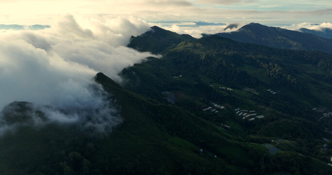 Aerial view of dramatic mountains cloaked in ethereal clouds, their peaks piercing the sky, Tambon Tap Tao, Chang Wat Chiang Rai, Thailand.
