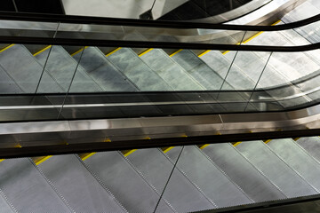 Fototapeta premium Modern Urban Architecture: Empty Commercial Escalators in Contemporary Shopping Mall Interior with Metal Railings and Glass Panels
