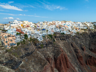 Aerial view of whitewashed buildings cascade down the volcanic cliffs, a harmonious blend of human architecture and nature's grandeur, Oia, Thira, Greece.