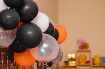 Cluster of black, orange, and silver balloons floating for a spooky or festive Halloween or birthday party theme