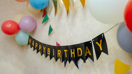 Happy birthday banner with colorful balloons and flags decorating a wall for a festive celebration...