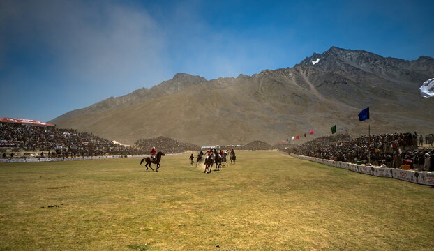 Shandur, Pakistan - 31 July 2017: View of a vibrant polo match unfolding on the high-altitude ground, framed by majestic mountains and cheering crowds.