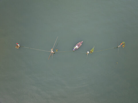 Aerial view of small wooden boats tethered in a line on the serene, calm waters of the river, Hội An, Quảng Nam, Vietnam.