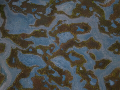 Aerial view of an intricate network of waterways weaving through marshland, creating a mosaic of blues and greens from above, Duxbury, Massachusetts, United States.