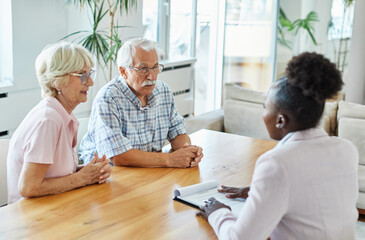 Obraz premium Happy senior old family couple clients make financial insurance estate business deal contract signing, agent lawyer, satisfied mature customers signing contract meeting bank manager agree on investmen