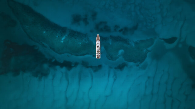 Aerial view of a luxury yacht cutting through the turquoise waters near Great Harbour Cay, Berry Islands, The Bahamas.