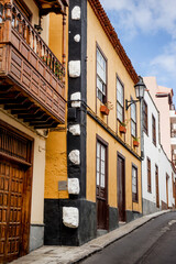 Garachico, Tenerife, Spain A charming street scene with a family walking past a colorful building, showcasing the unique architecture of the town