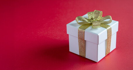 Obraz premium White Gift Box with Gold Ribbon on Red Background