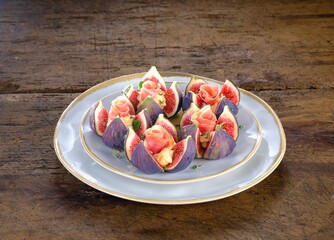 On rustic wood, artfully sliced Figs are stuffed with savory Prosciutto. A delectable starter, presented on elegant, stacked Plates, evokes an italian summer