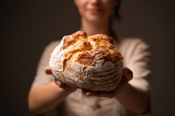 Artisan baker presenting rustic handmade bread loaf, showcasing traditional craftsmanship and natural quality
