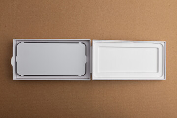 Minimalist open smartphone box on cardboard background