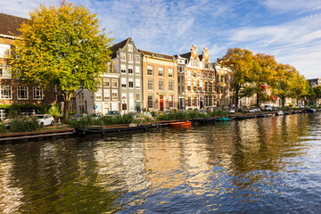 Series of traditional row houses along the Singel canal seen during a golden hour afternoon, with...