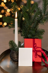 Empty Christmas postcard mockup on table, red presents box, candle light and pine branches, festive holiday background, soft focus