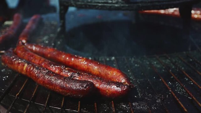 Sausages grilling on hot barbecue street food.