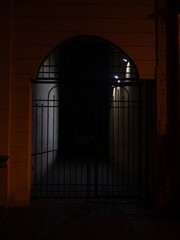 Dark Arched Gate with Metal Bars at Night, Historic Urban Architecture and Moody Shadowy Entrance