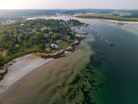 Aerial view of the coastline where the land meets the sea, boats bob gently on the water near a sandy beach, Gloucester, Massachusetts, United States.