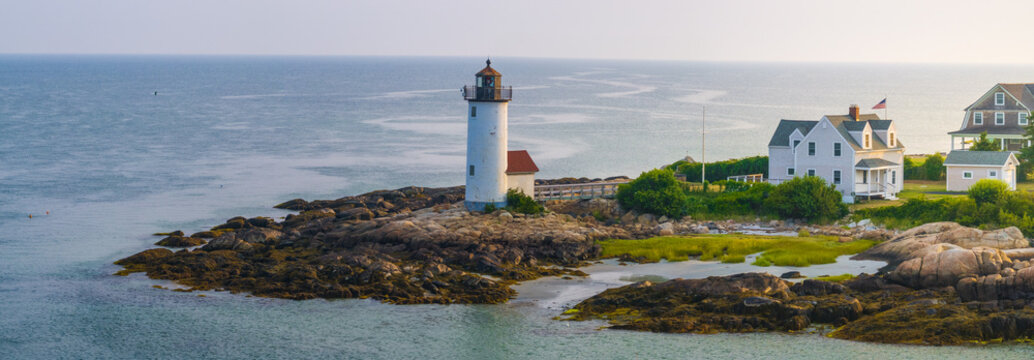 Aerial view of the iconic white tower of the Nubble Lighthouse stands proudly on a rocky outcrop against the vast ocean, Gloucester, Massachusetts, United States.