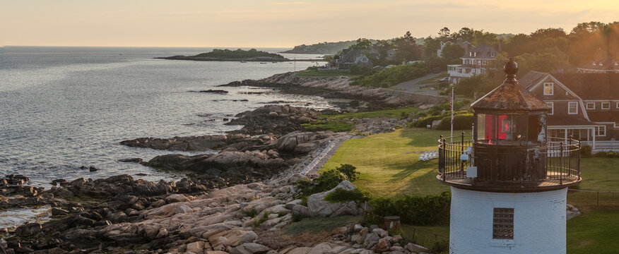 Aerial view of the striking white lighthouse standing tall against the rocky coastline and calm ocean, Gloucester, Massachusetts, United States.