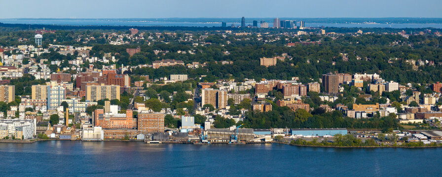 Aerial view of a vibrant cityscape where buildings meet the tranquil waters, with distant skyscrapers punctuating the horizon, New York, New York, United States.