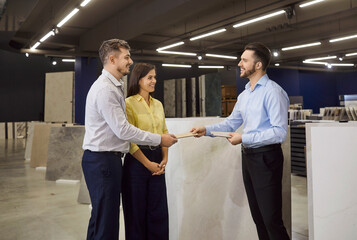 Sale manager meets consulting couple customers in show room, marketing, showing clients modern samples, happy family making purchase, choosing utensils for home repair, bath room, seller helping