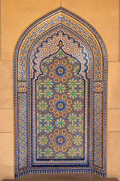 View of vibrant, colorful mosaic tilework, with intricate geometric patterns set within a tan stone archway, a cultural testament, Muscat, Muscat Governorate, Oman.