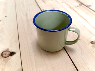 Iron enamel empty mug with wooden background.