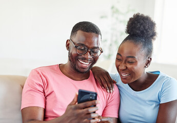 Happy young couple having fun using smartphone  during oline video call conversation or shopping or using an app at home