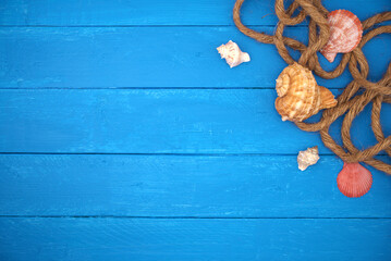 Seashells with rope and sand on blue wooden. Sea summer vacation background with space for the...