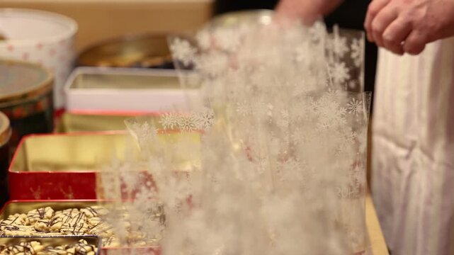 Man filling transparent cookie bags with homemade Christmas cookies in festive holiday scene