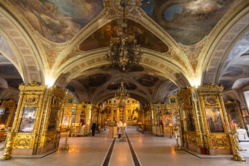 View of golden ornate interiors, soaring arched ceilings adorned with frescoes, and chandeliers casting a warm glow in a grand cathedral, Moskva, Moskva, Russia.