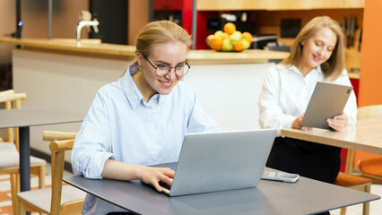 Obraz premium Women working on laptops in a cafe setting