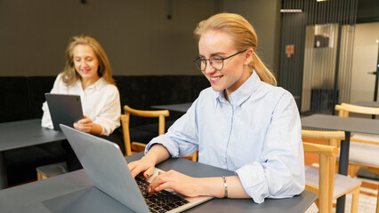 Obraz premium Two women working at a table with laptops