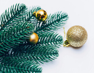 Golden Christmas Ornament Hanging on Lush Green Pine Branches Against a Clean White Background in Minimalist Holiday Still Life Photography