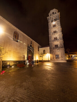 San Cristobal de La Laguna, Spain - 17 December 2016: View of the illuminated Iglesia de la Concepci&oacute;n, its bell tower rising against the night sky, casting a warm glow on the cobblestone square.