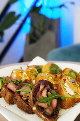 Gourmet appetizer platter featuring sliced steak on toasted bread, colorful toppings, and fresh herbs, beautifully arranged for an elegant dining experience