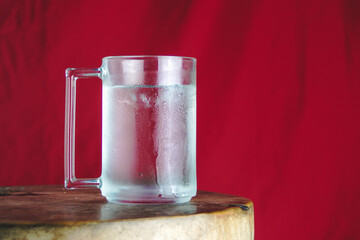 Chilled Glass Mug of Iced Water with Condensation on Red Background