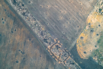 Military trenches and defensive fortifications dug in a field near a dirt road, aerial view of a scarred battlefield landscape and threat to Europe