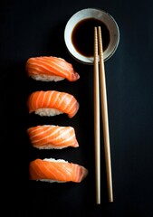 Four pieces of salmon nigiri sushi with soy sauce and chopsticks