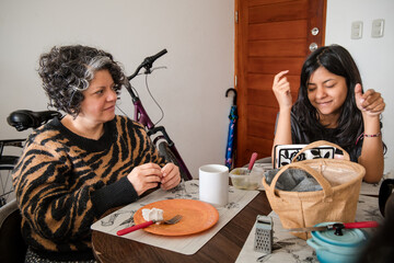 Mother and daughter are sitting at a table, one of them is wearing a striped shirt