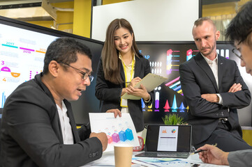 Male and female businesspeople team working together in business meeting with company statistic chart on screen background