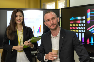 Male and female businesspeople team working together in business meeting with company statistic chart on screen background