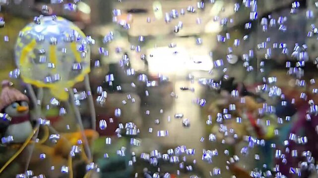 Goldfish and guppies swim in an aquarium filled with air bubbles. Yellow jellyfish and toy penguin float in the background. The air bubbles in the aquarium come from the air pump out of the generator
