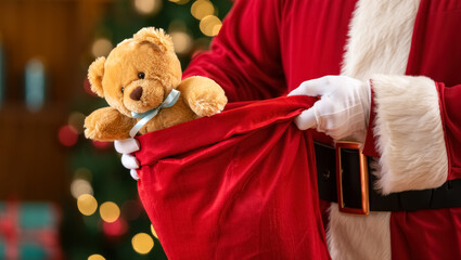 Close-up of Santa Claus in red costume pulling a teddy bear gift from a red sack, symbolizing a Christmas present, with warm festive lights in the background and a cozy holiday mood