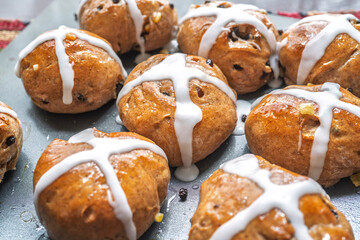 Homemade hot cross buns freshly glazed and on a cookie sheet.